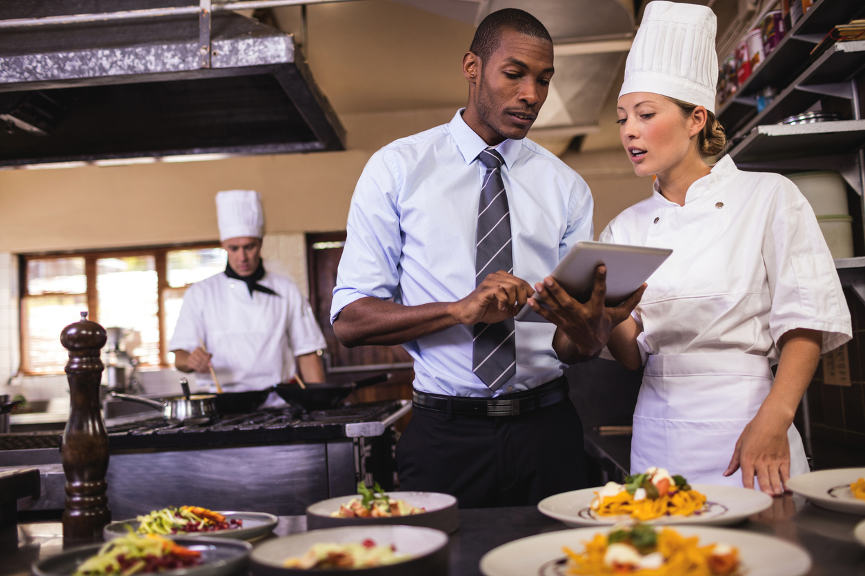 Male manager and female chef using digital tablet in kitchen for strategic procurement solutions