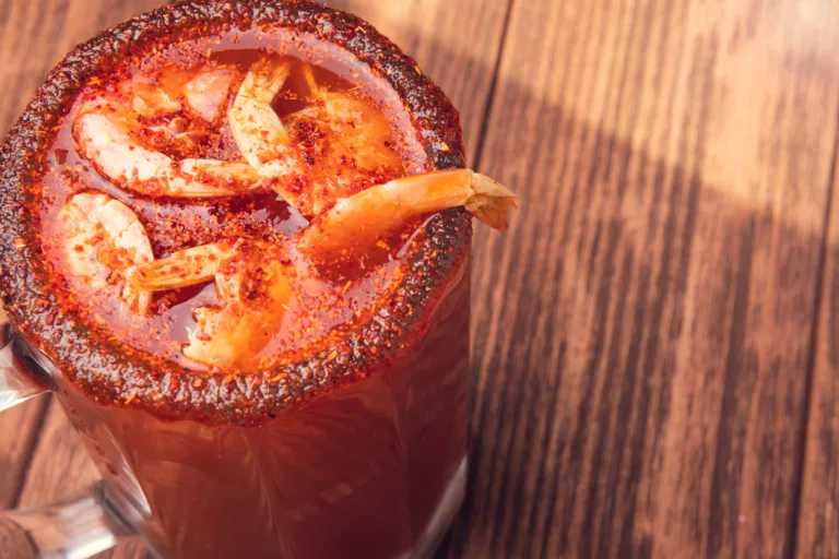 Michelada beer with tomato juice. Clamato with beer on wooden table. Mexican drink. Concept of mexican frink