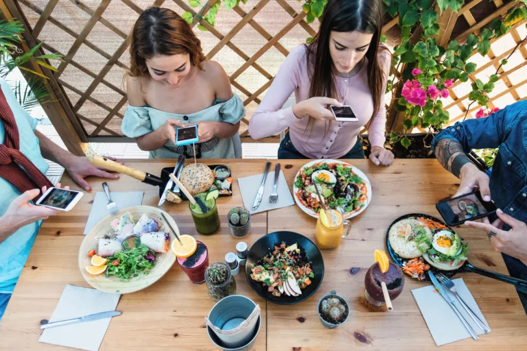 Young people taking food pictures with mobile smartphone to share on social media while having healthy meal in bar restaurant - Youth generation z and technology concept