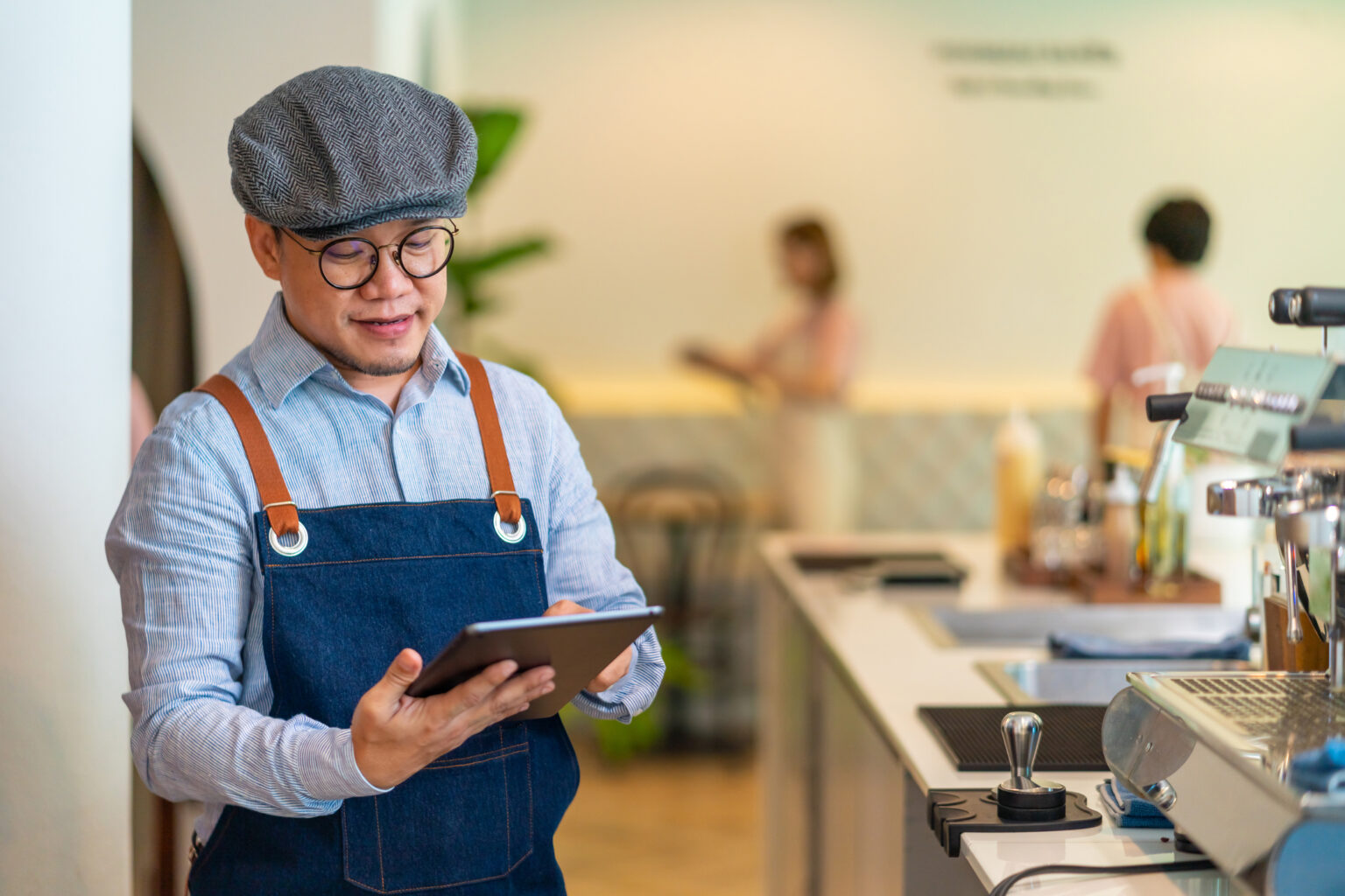 Asian man coffee shop owner checking inventory on digital tablet restaurant furniture