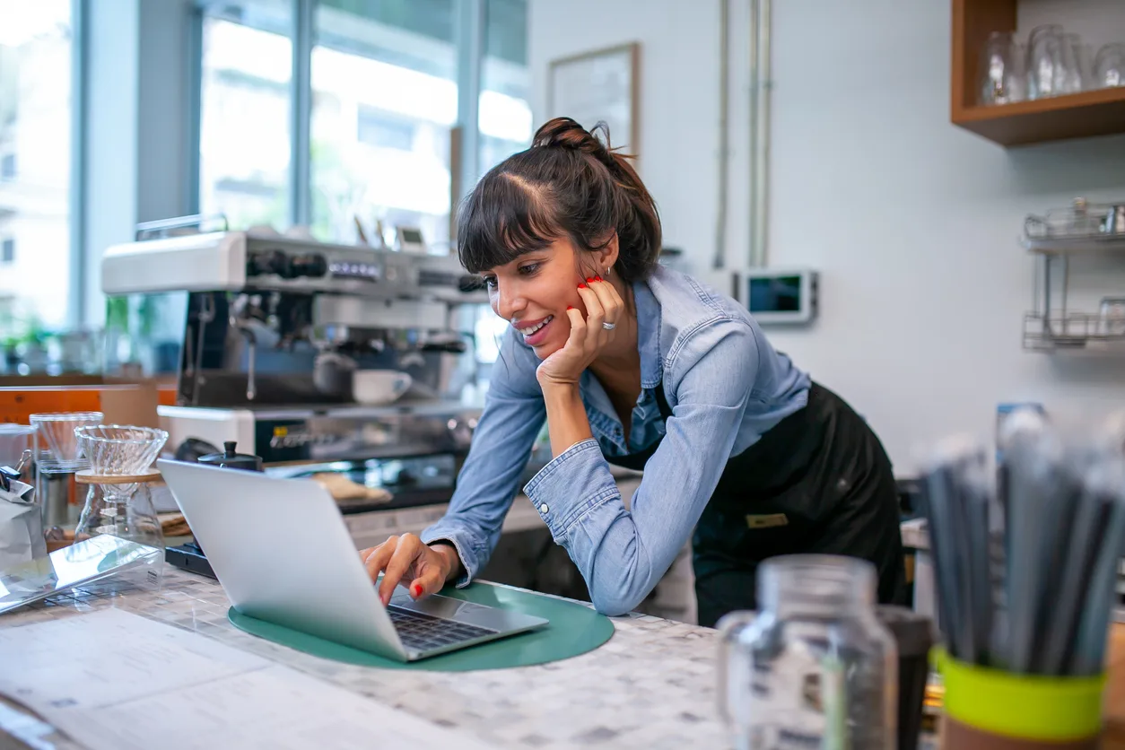 happy woman barista using laptop for take order from customer in coffee shop. group purchasing programs