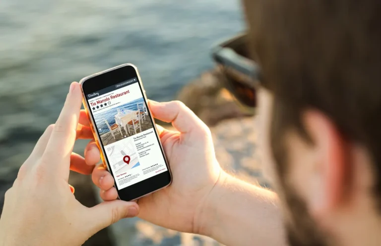 man on the coast using his smartphone browsing online directory of good and bad restaurant reviews. All screen graphics are made up.