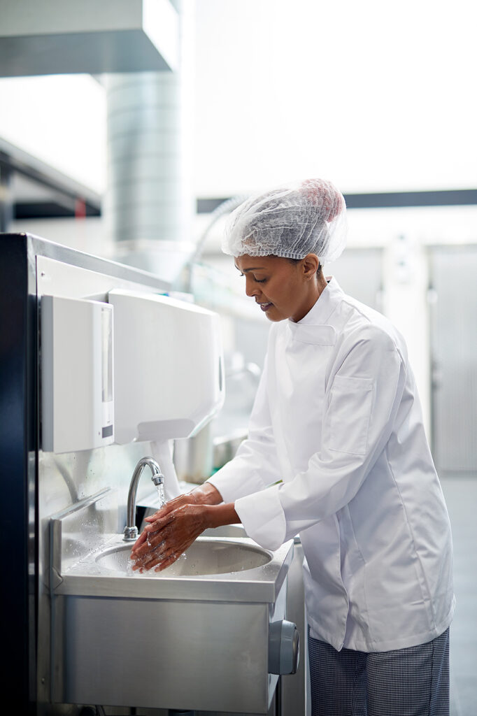 A female chef washes her hands, sanitizing before going back to work.