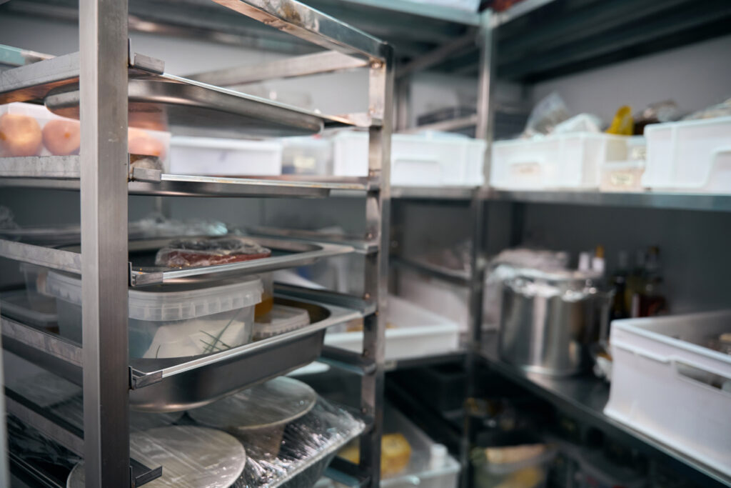 Focus of dishes on shelves in blurred refrigerator storage in restaurant stock phot. restaurant equipment maintenance