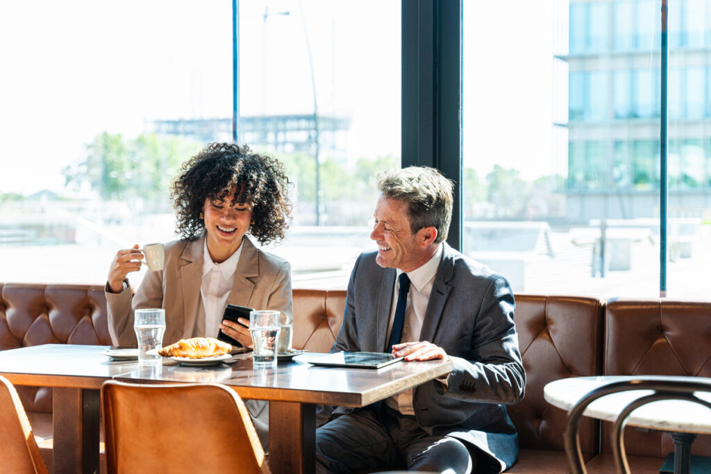 Happy man and woman in suits have a meeting at a cafe.