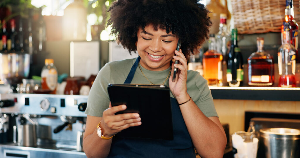 Tablet, bartender and happy woman on cellphone call, discussion and order alcohol stock, store delivery or distribution. Commerce, phone and small business owner consulting on drinks supply chain custom contracting for foodservice