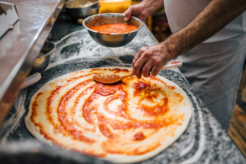 Close-up image of chef making pizza.