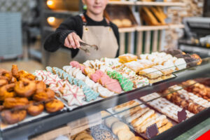 Pastry chef arranging colorful christmas cookies in a bakery display case, showcasing a variety of festive treats