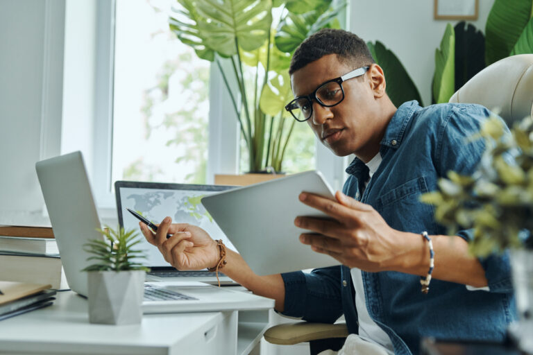 Busy young mixed race man using technologies while working in the office